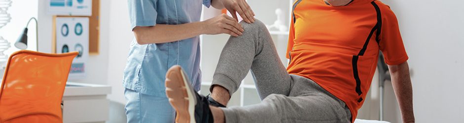 Knee problems. Pleasant senior man looking at the nurse while having a knee massage